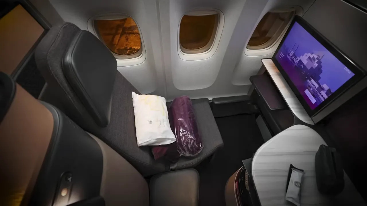 QSuite seat showing pillow and blanket on the seat with table and in-flight screen