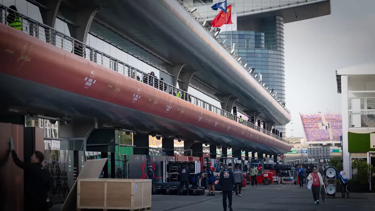 Paddock walkway with elevated garage structure, team equipment and crew working