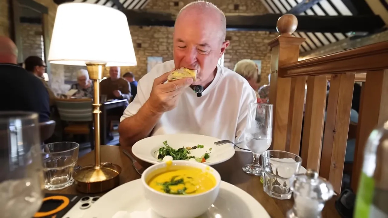 Bowl of yellow soup with herbs beside slices of sourdough bread and butter