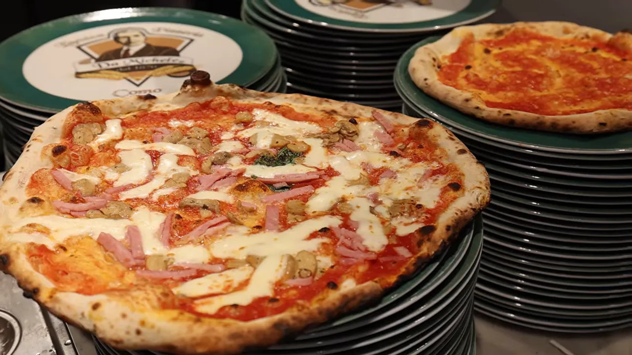 Freshly baked pizza on stacked plates inside a pizzeria