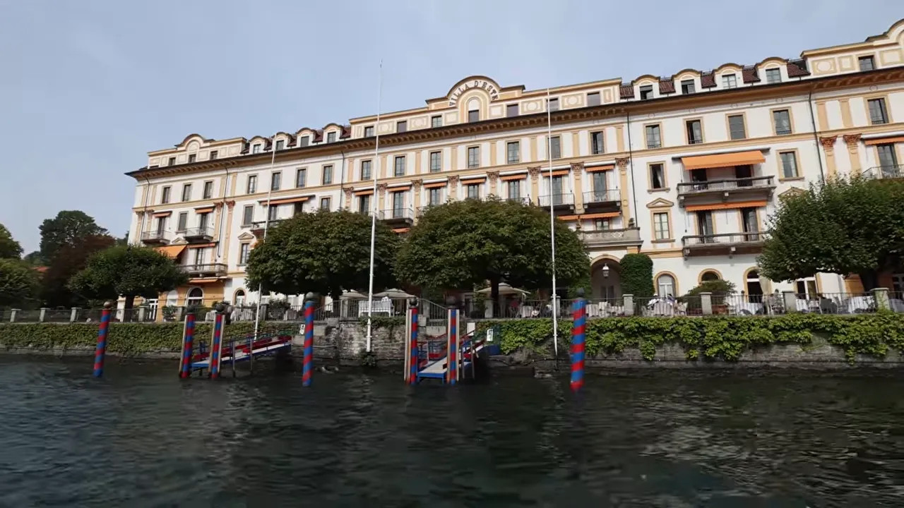Grand cream-coloured lakeside hotel with balconies viewed from a boat