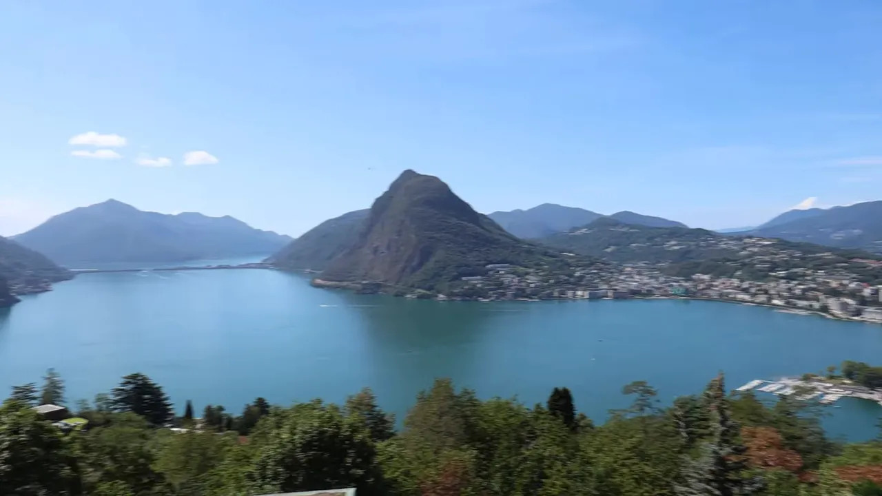 Panoramic view of Lake Lugano surrounded by mountains