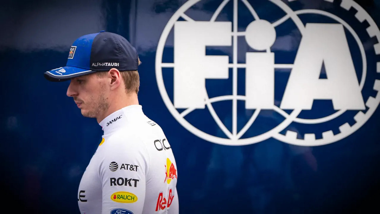 Max Verstappen walking past a large FIA logo wall