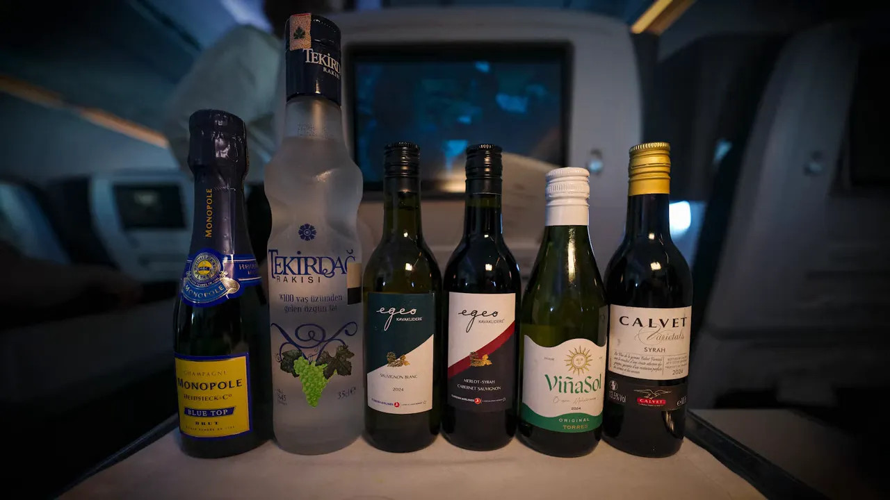 Mini bottles of champagne, raki, and wine lined up on a tray table