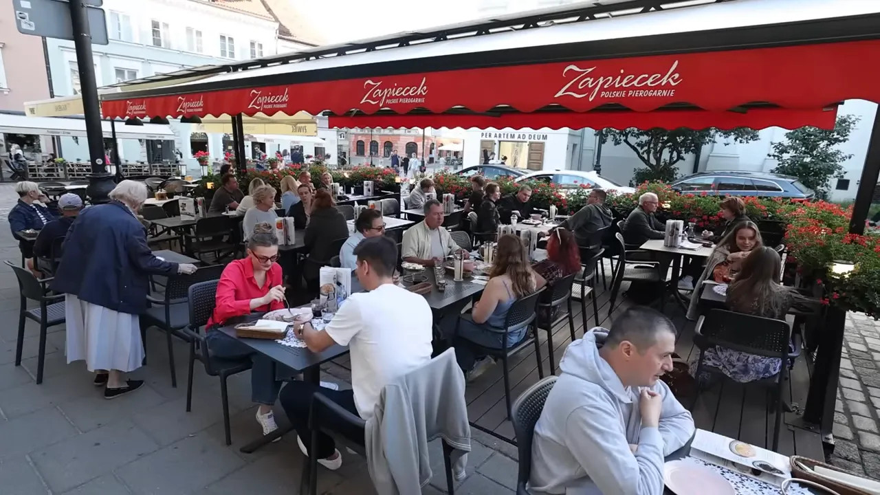 busy outdoor restaurant seating under a red awning in Warsaw Old Town