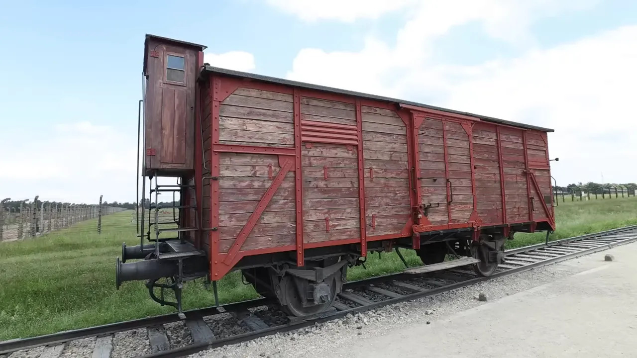 red wooden rail carriage standing on tracks at Birkenau