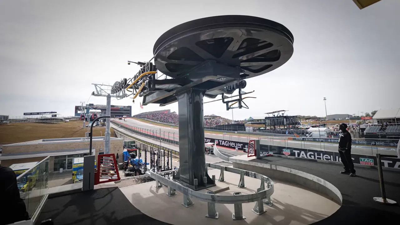Gondola terminal with a large overhead wheel and cabins above the circuit