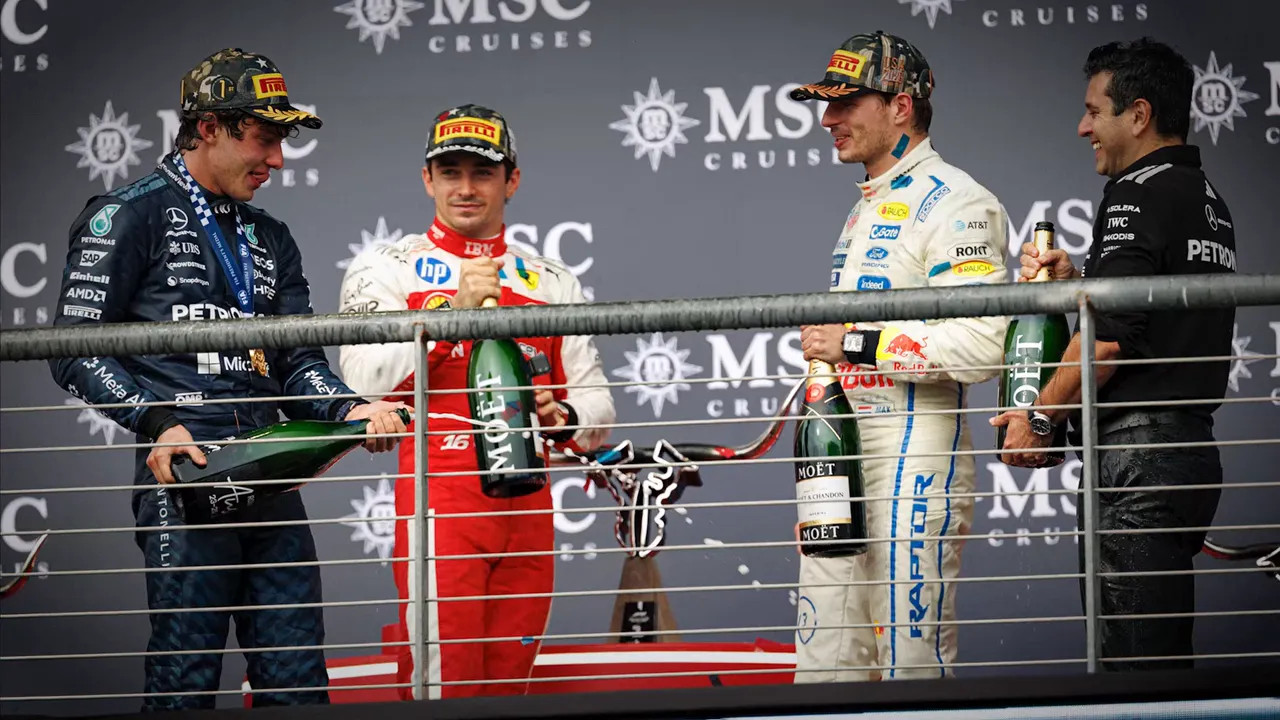 Kimi Antonelli holding a bottle beside the other podium finishers and a team representative