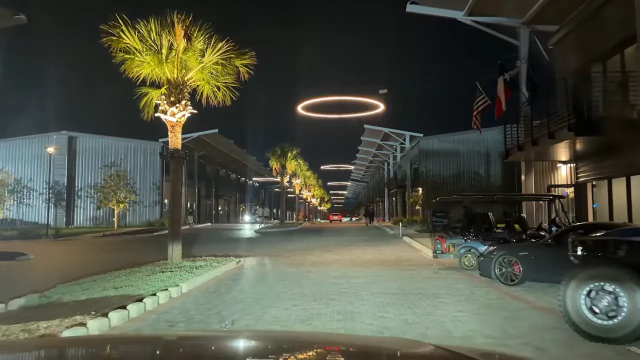 White sports car and large off-road racing vehicle inside an illuminated garage