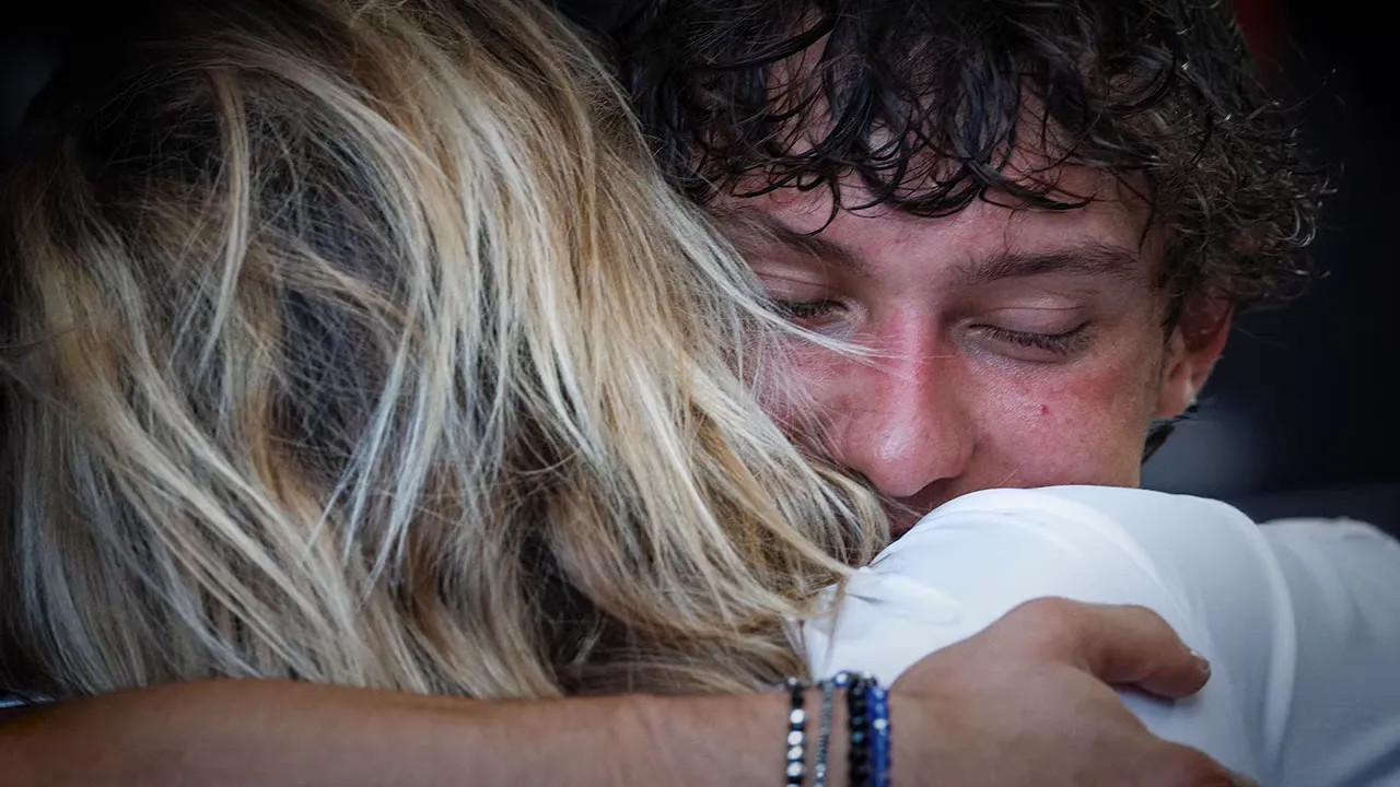 Kimi Antonelli hugs a woman with his eyes closed after the race