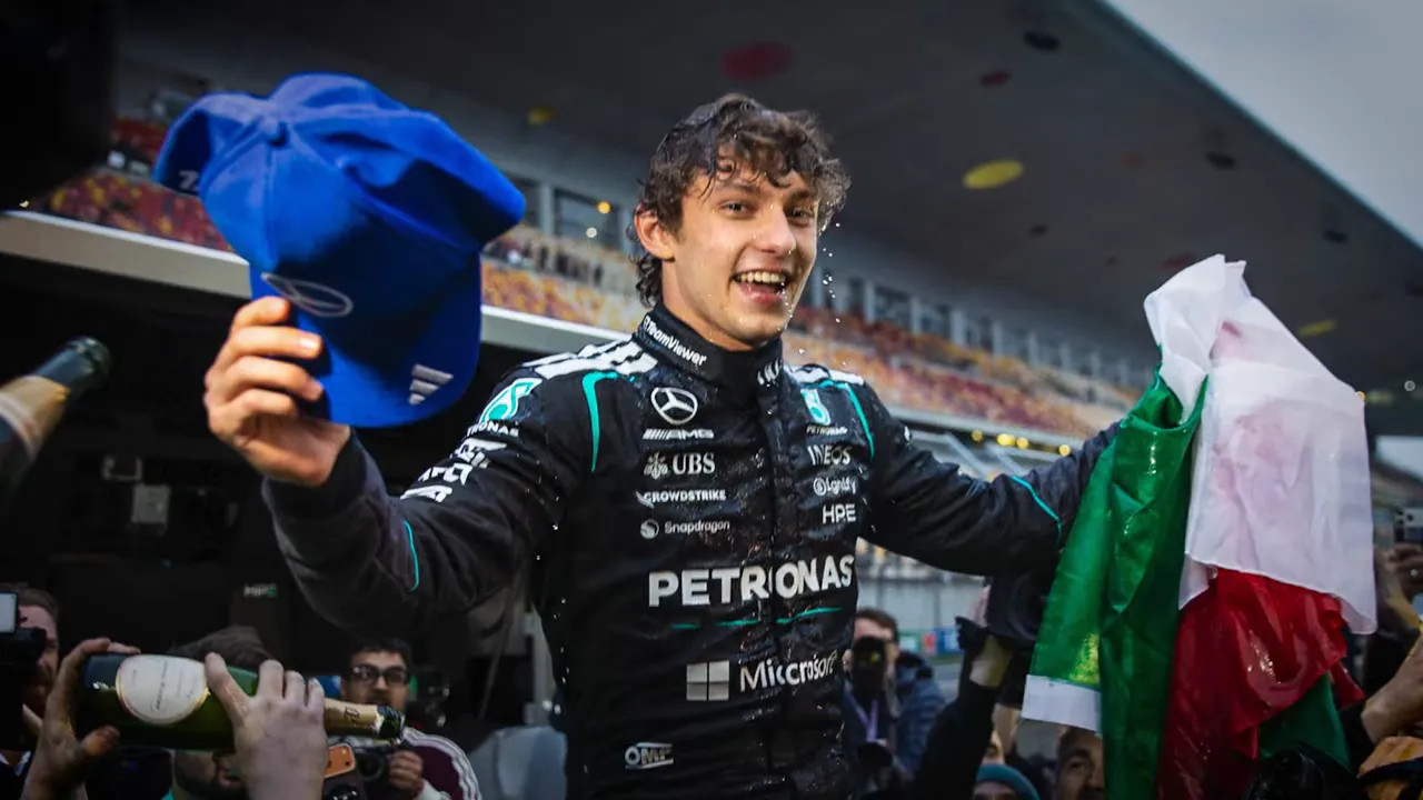driver celebrating on the podium area holding a hat and Italian flag with champagne spray
