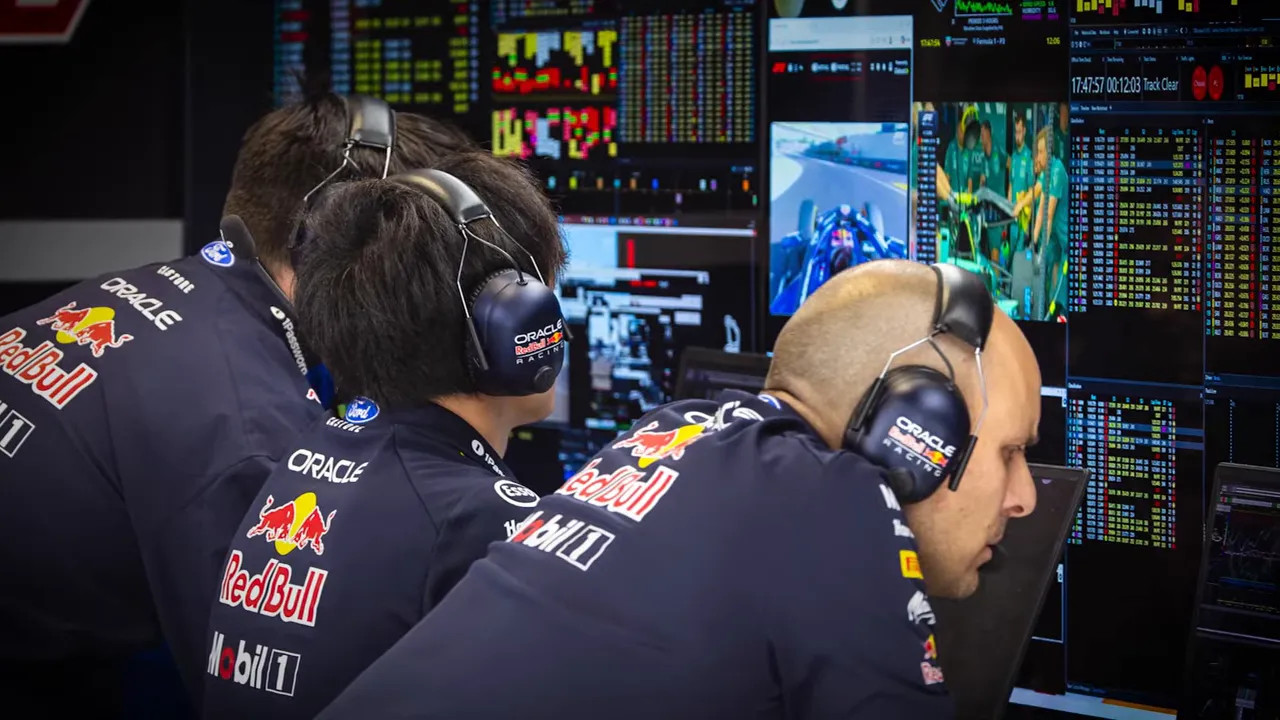 Red Bull engineers studying multiple data and timing screens in the garage