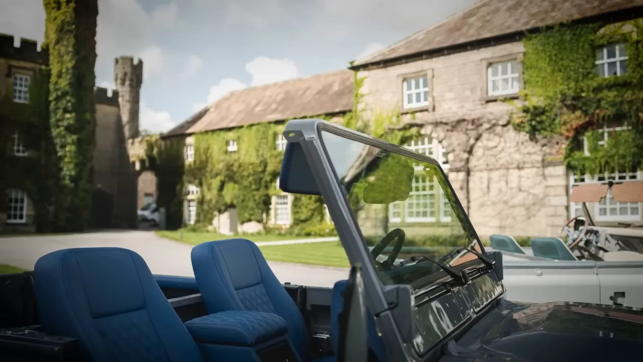 Open-top Land Rover Defender with blue seats and driver view
