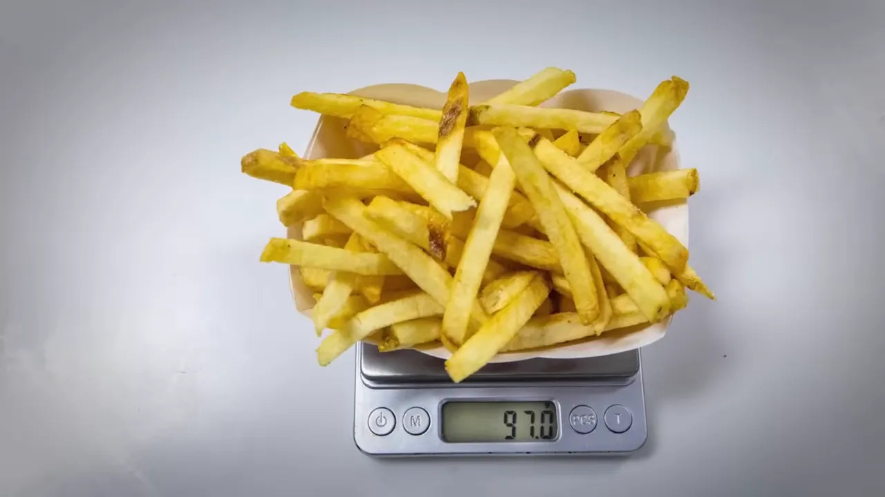 Basket of fries sitting on a digital kitchen scale showing 97.0 g