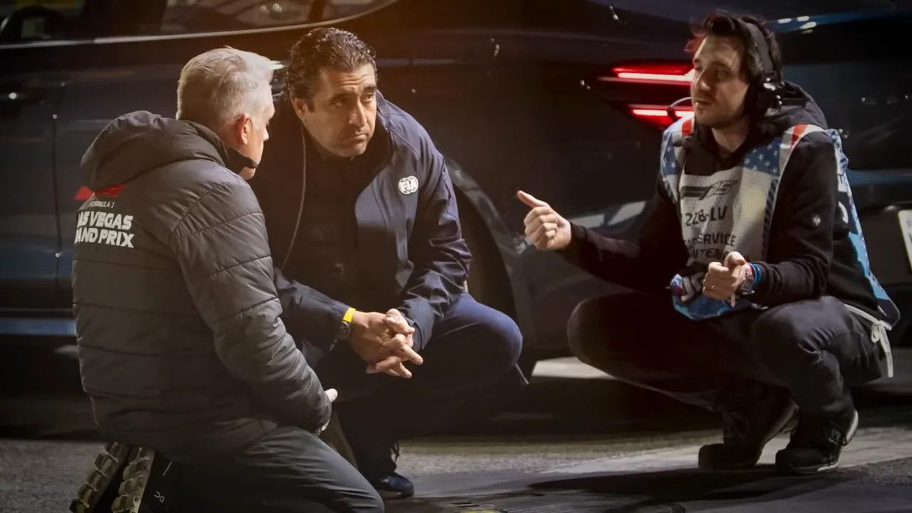 Three track officials crouched around a manhole cover on the street circuit discussing repairs