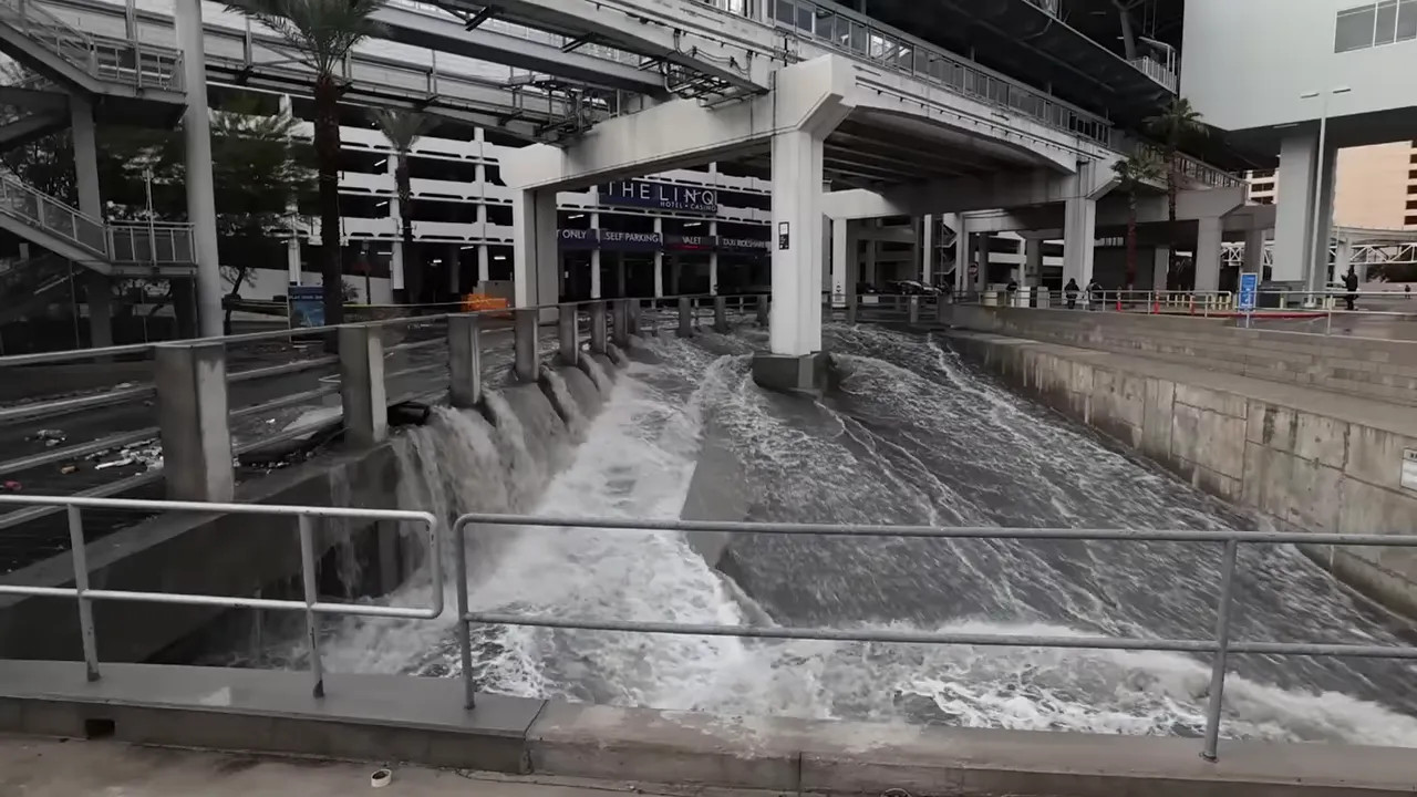Wide view of cascading floodwater through a drainage channel and runoff area at The LINQ, Las Vegas