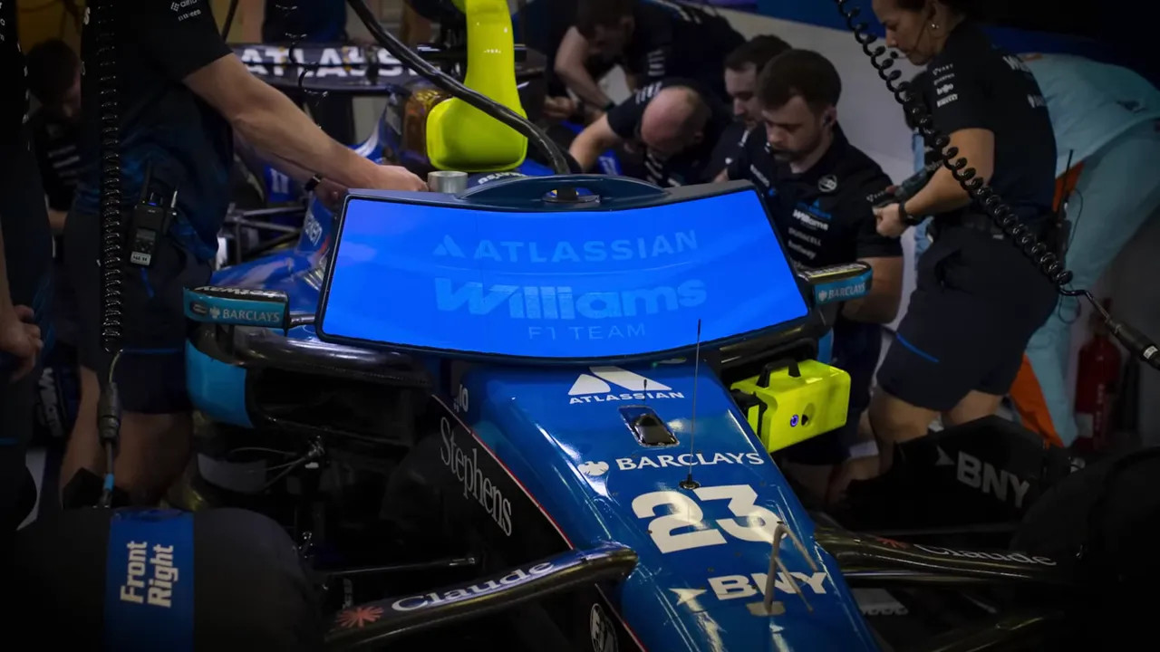 Williams F1 car in the garage with a lowered blue display panel showing team and sponsor branding
