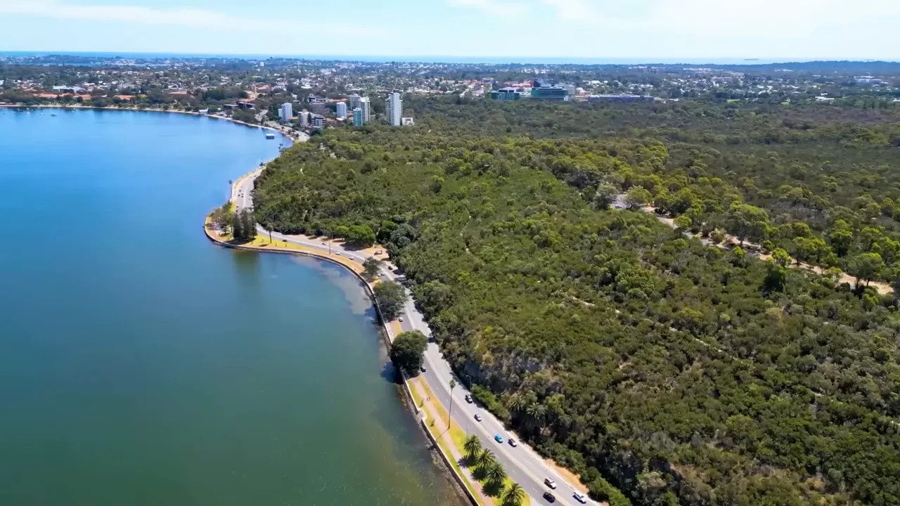 Aerial view of a Perth riverfront road with dense green bushland