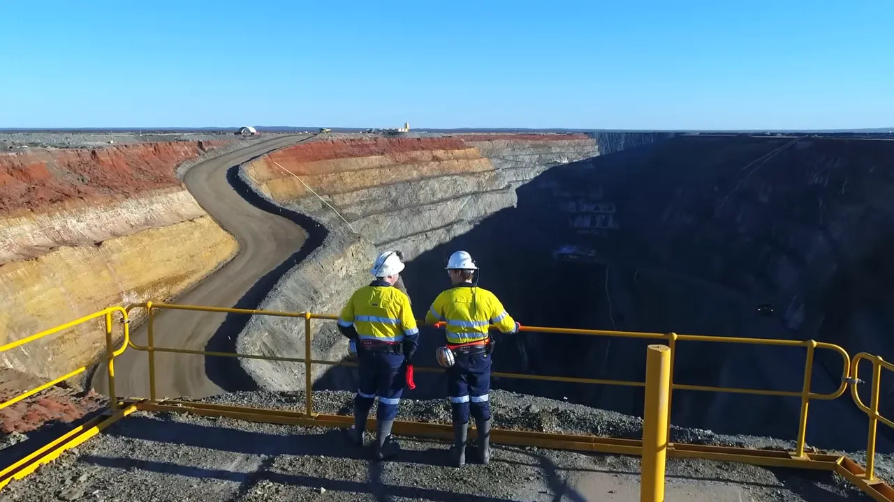 Workers on an industrial lookout with a winding mining/processing landscape near Perth