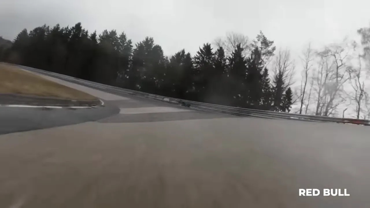 Track view through fog on a winding circuit with racing line and trees in the background