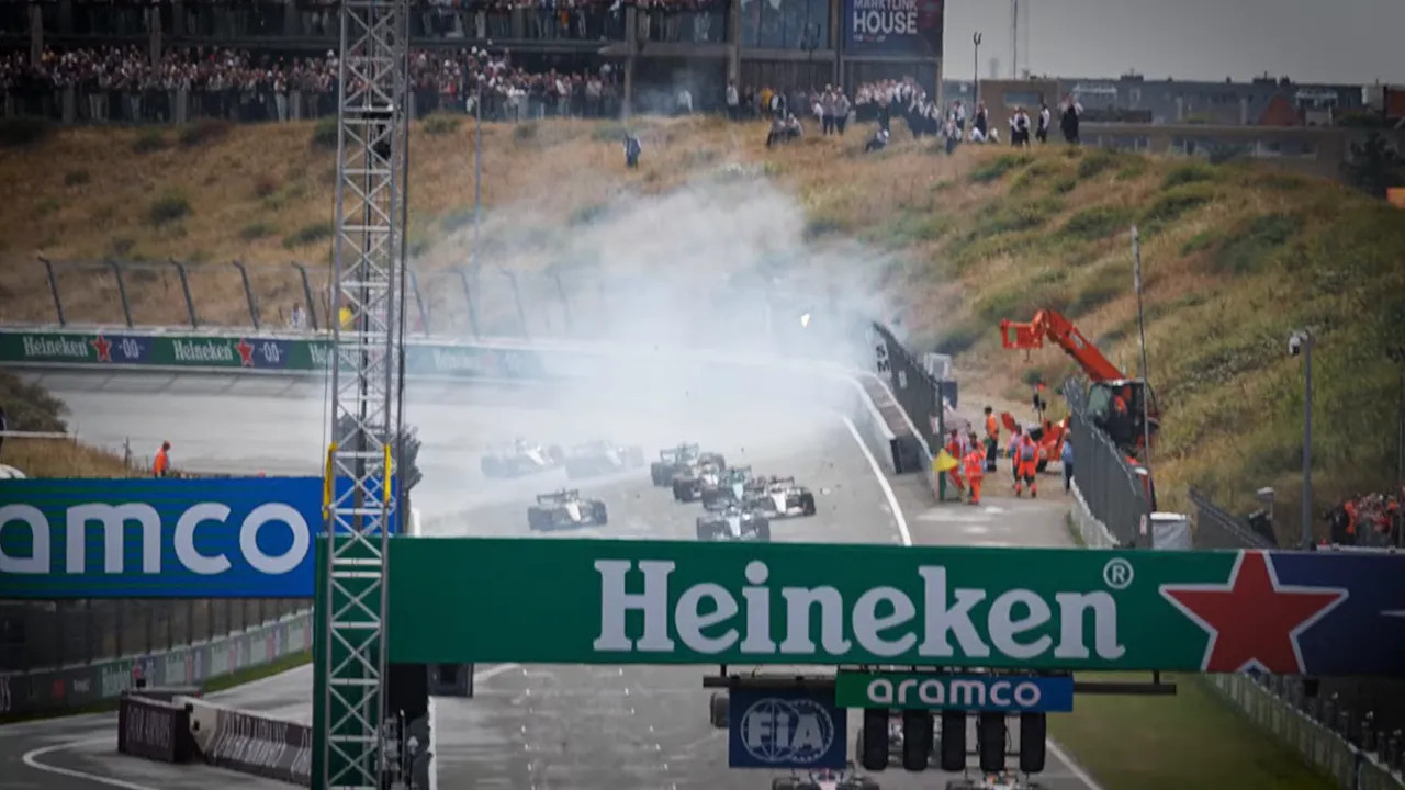 Formula 1 cars drive through smoke near a Heineken bridge at Zandvoort