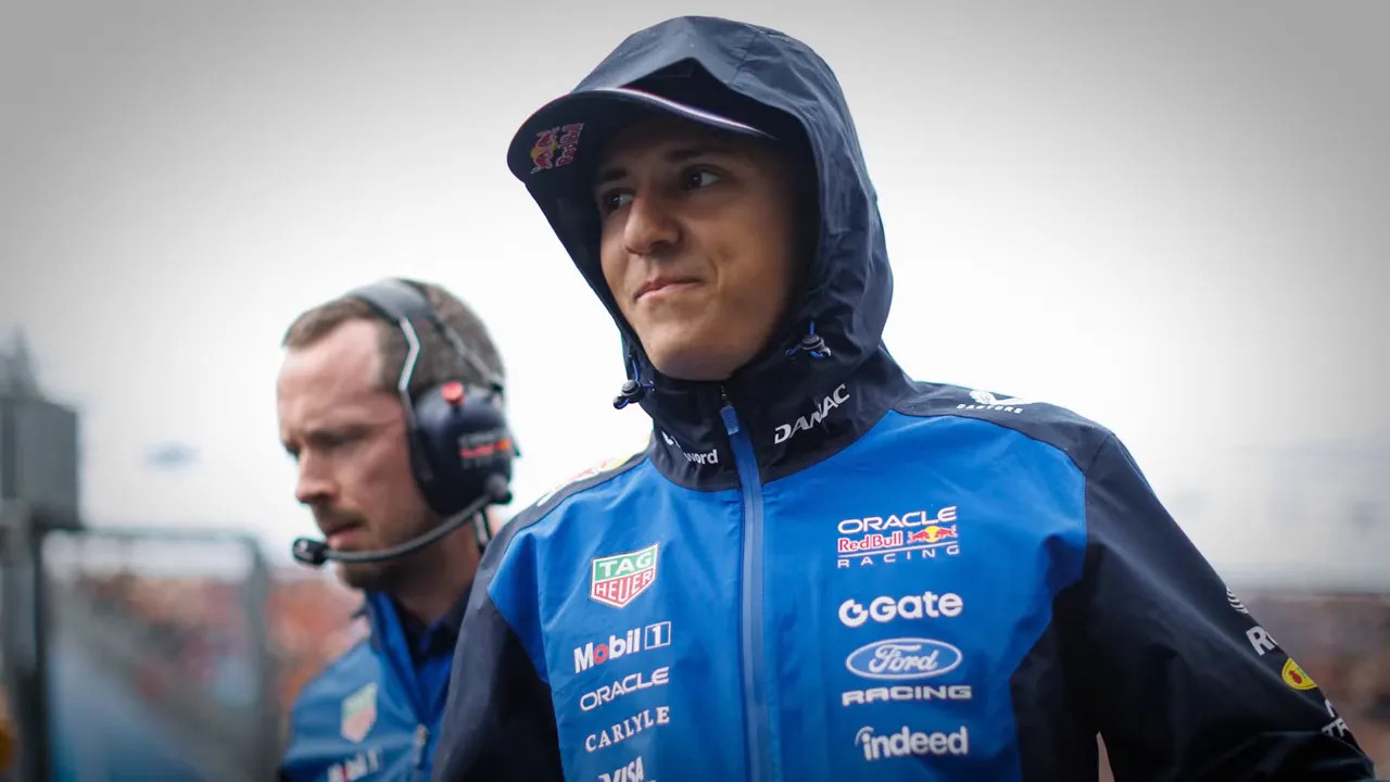 Isack Hadjar wears a hooded Racing Bulls team jacket in wet weather