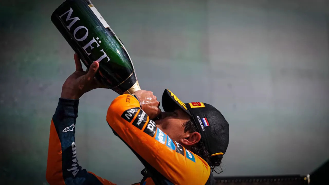 Lando Norris lifts a trophy beside championship points totals on screen