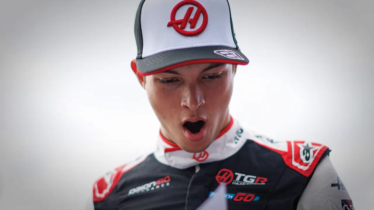 Oliver Bearman in a Haas race suit and cap with his mouth open in a yawn