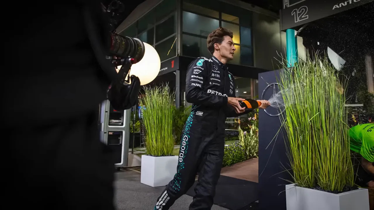 George Russell grabs champagne and starts spraying during Mercedes' celebration
