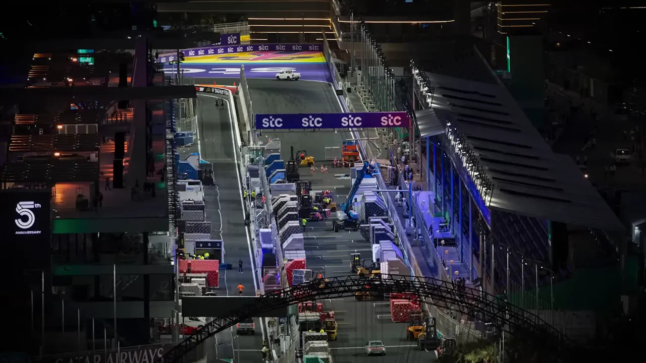 Aerial view of a pit lane stacked with freight crates, vehicles and crew preparing the garage area