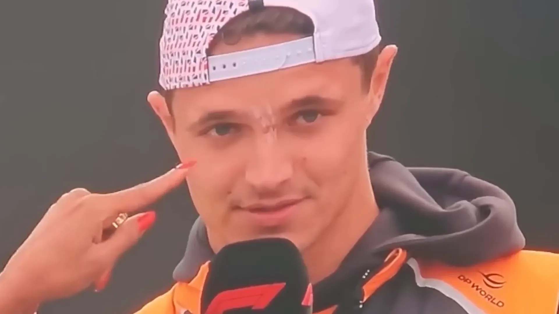 Lando Norris reacting after receiving a hit to his nose from a photographer on the fence