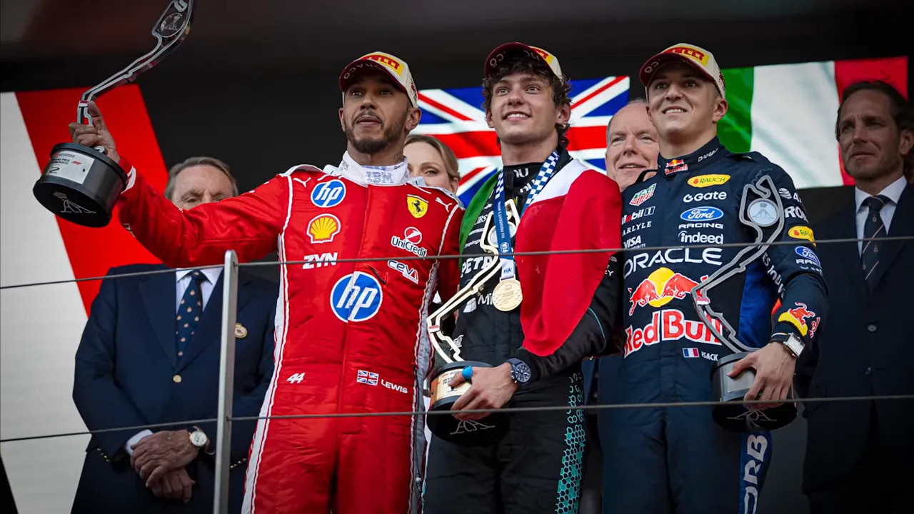 Three Monaco Grand Prix podium finishers standing with trophies on the podium
