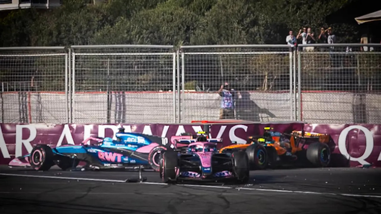 Two Alpine Formula 1 cars stopped close together beside a trackside barrier