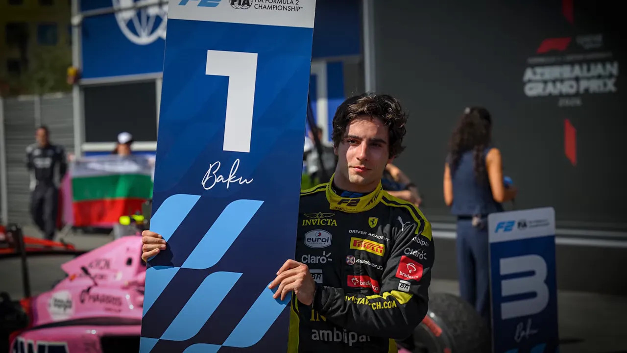 Young racing driver in a black suit raising a trophy on a podium