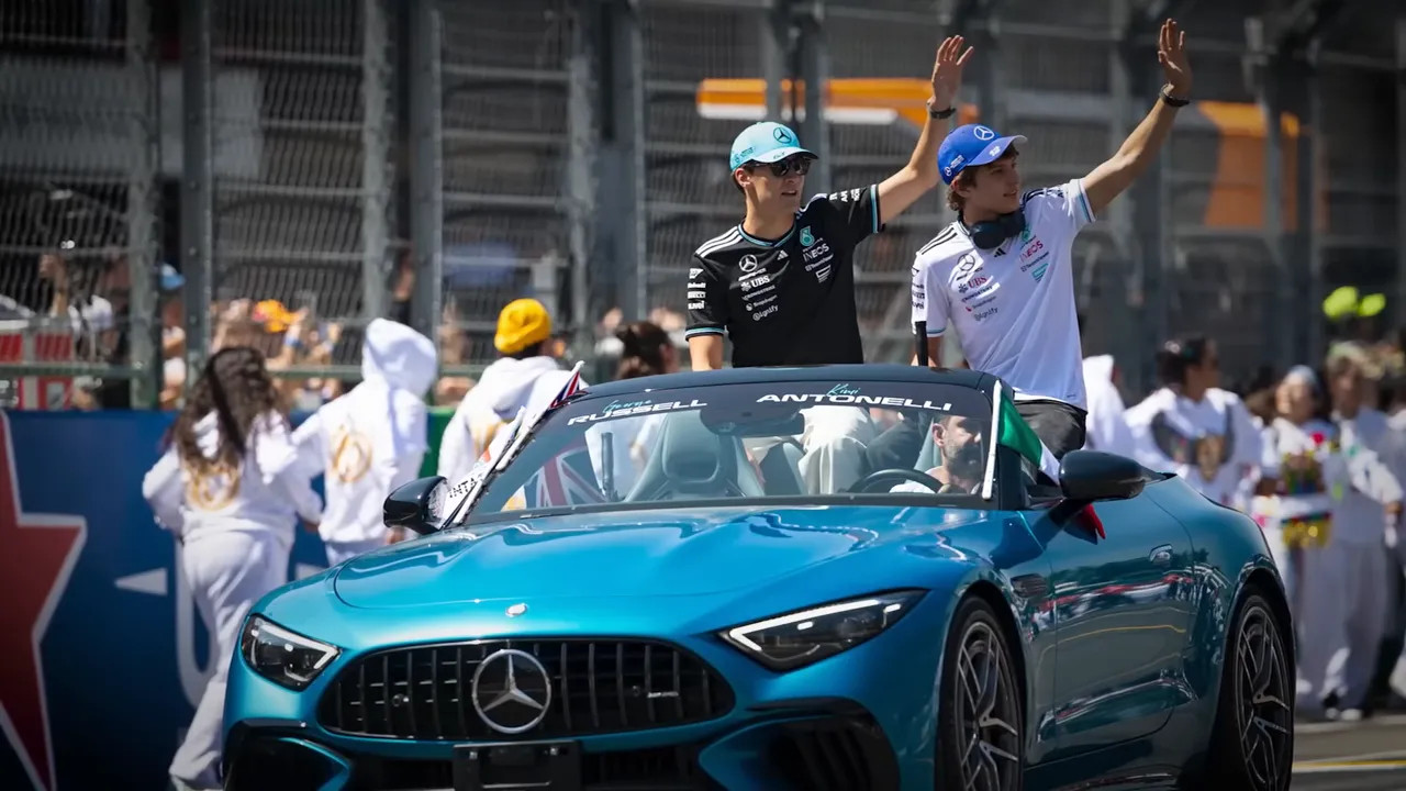 F1 cars on the track with drivers waving to the crowd