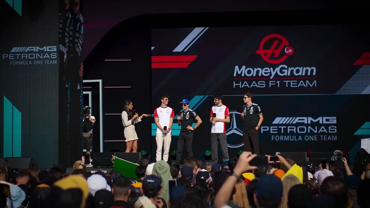 F1 drivers standing on a stage during a public media event with crowd phones raised