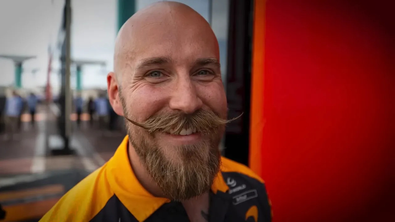 Close portrait of Oscar Piastri's trainer with a long curled moustache
