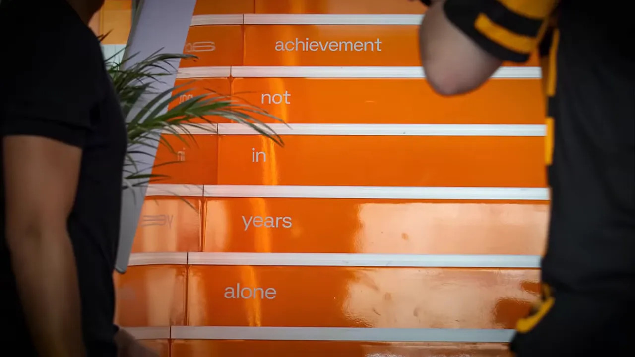 Orange staircase inside McLaren hospitality with text and Bruce McLaren name at the base