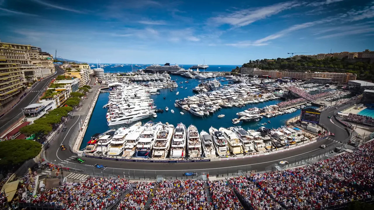 Wide view of Monaco harbour packed with yachts beside the race circuit and grandstands