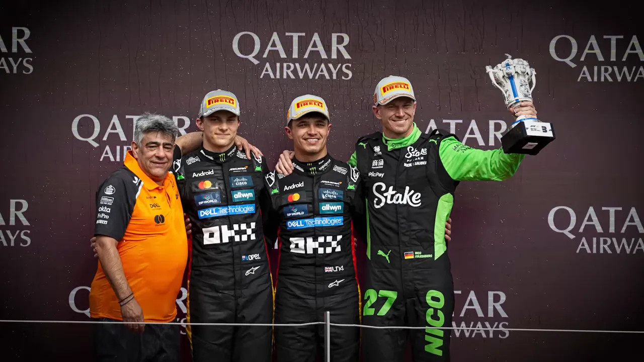 Three drivers standing on an F1 podium in front of a sponsor backdrop, one driver holding the winner's trophy aloft