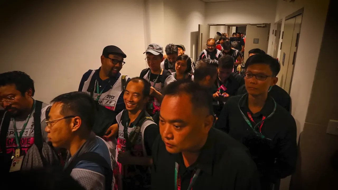 crowded corridor of photographers packed closely together waiting indoors