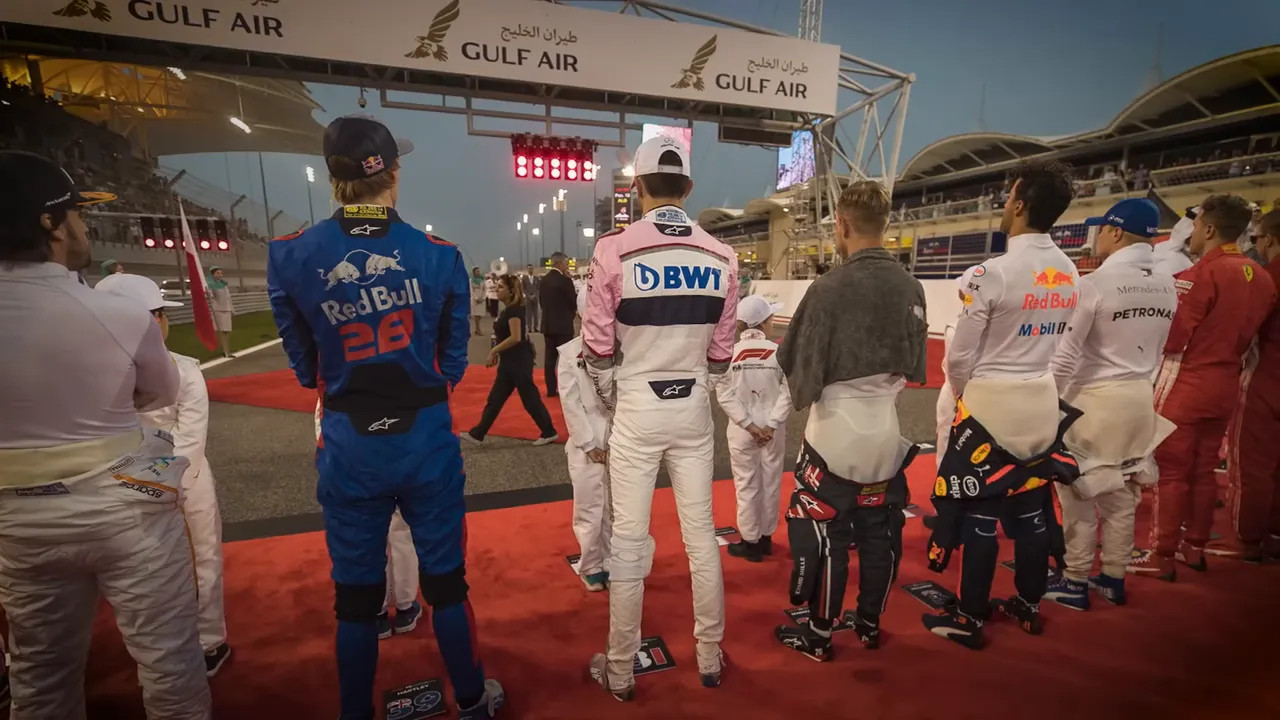 drivers standing on the grid during the national anthem with people behind them