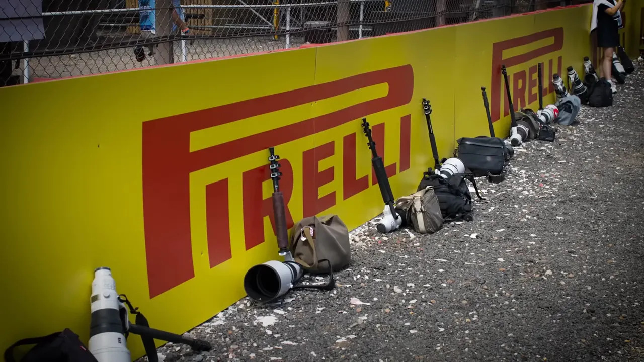 long telephoto lenses and camera bags lined up beside a yellow Pirelli barrier