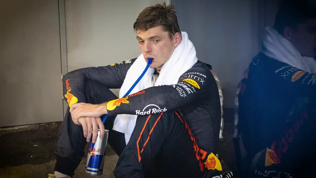 Max Verstappen sitting on the floor in Red Bull kit looking exhausted