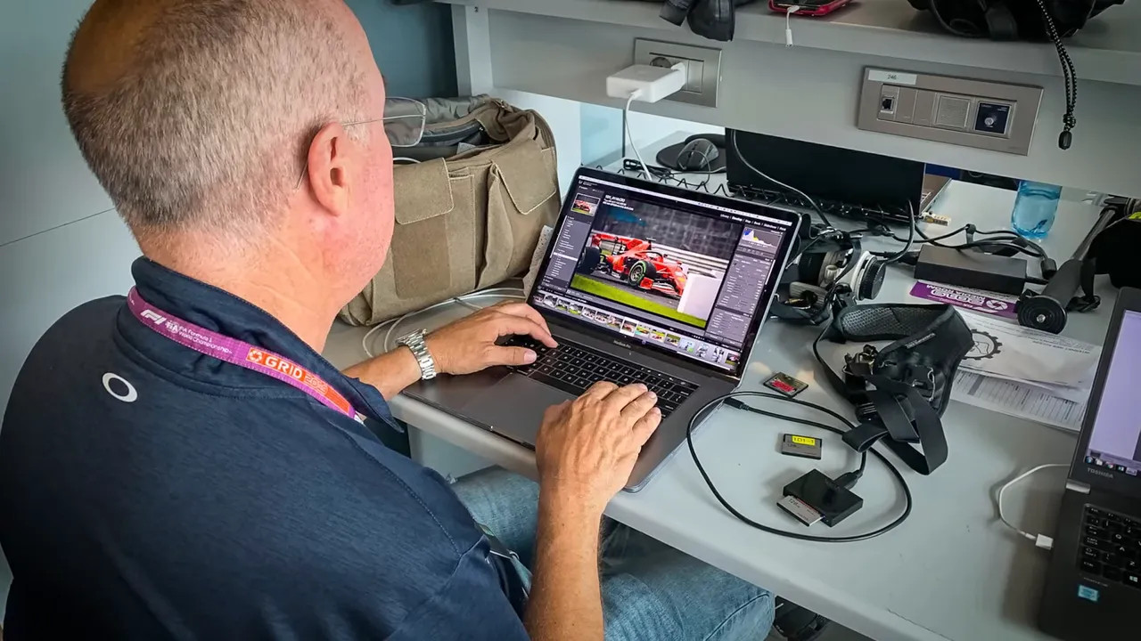 photographer editing images on a laptop at a media centre desk