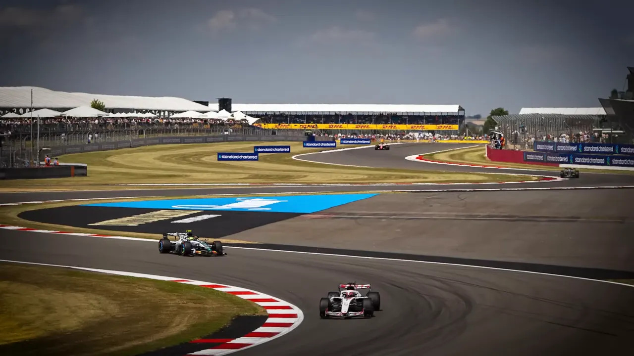 wide view of Silverstone circuit with several cars and grandstands in the background