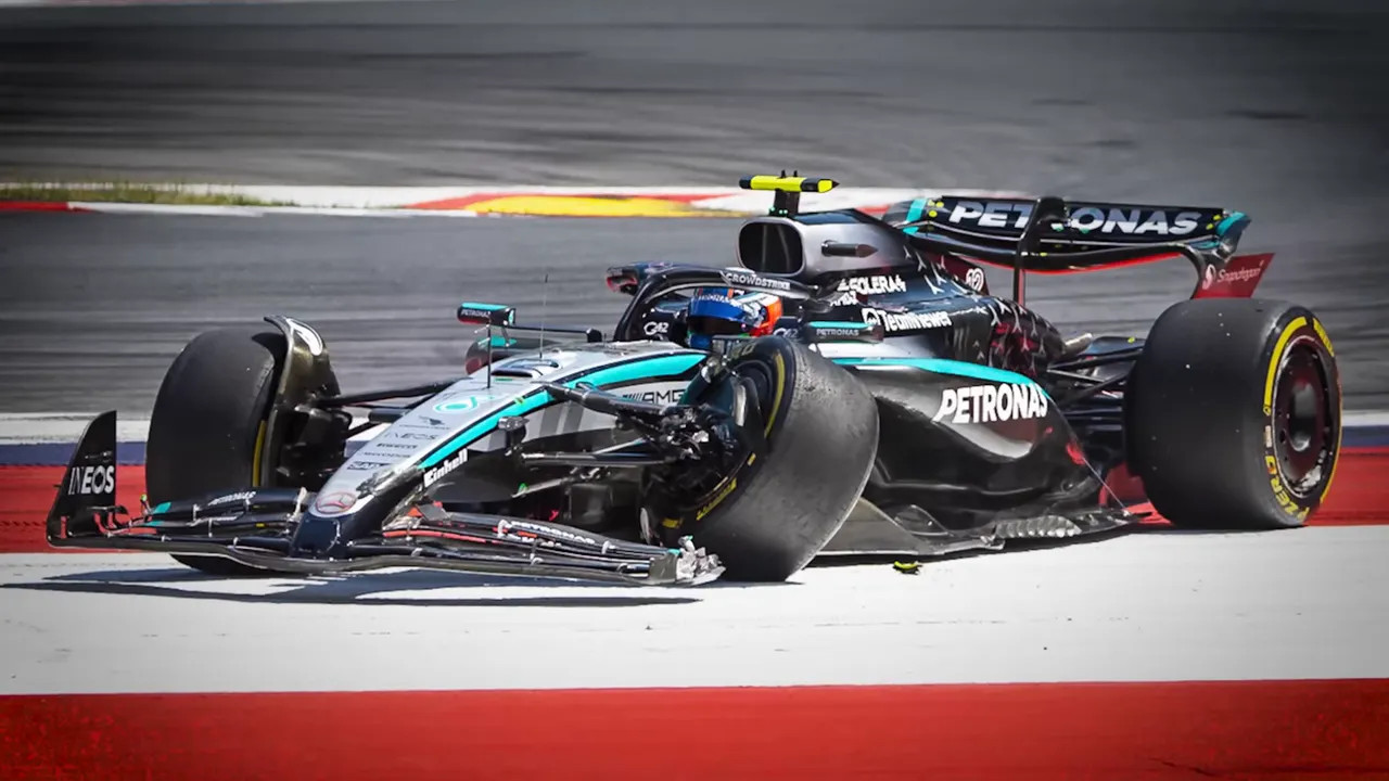 Damaged Mercedes F1 car with a shredded front wheel and broken front wing stopped at the side of the track