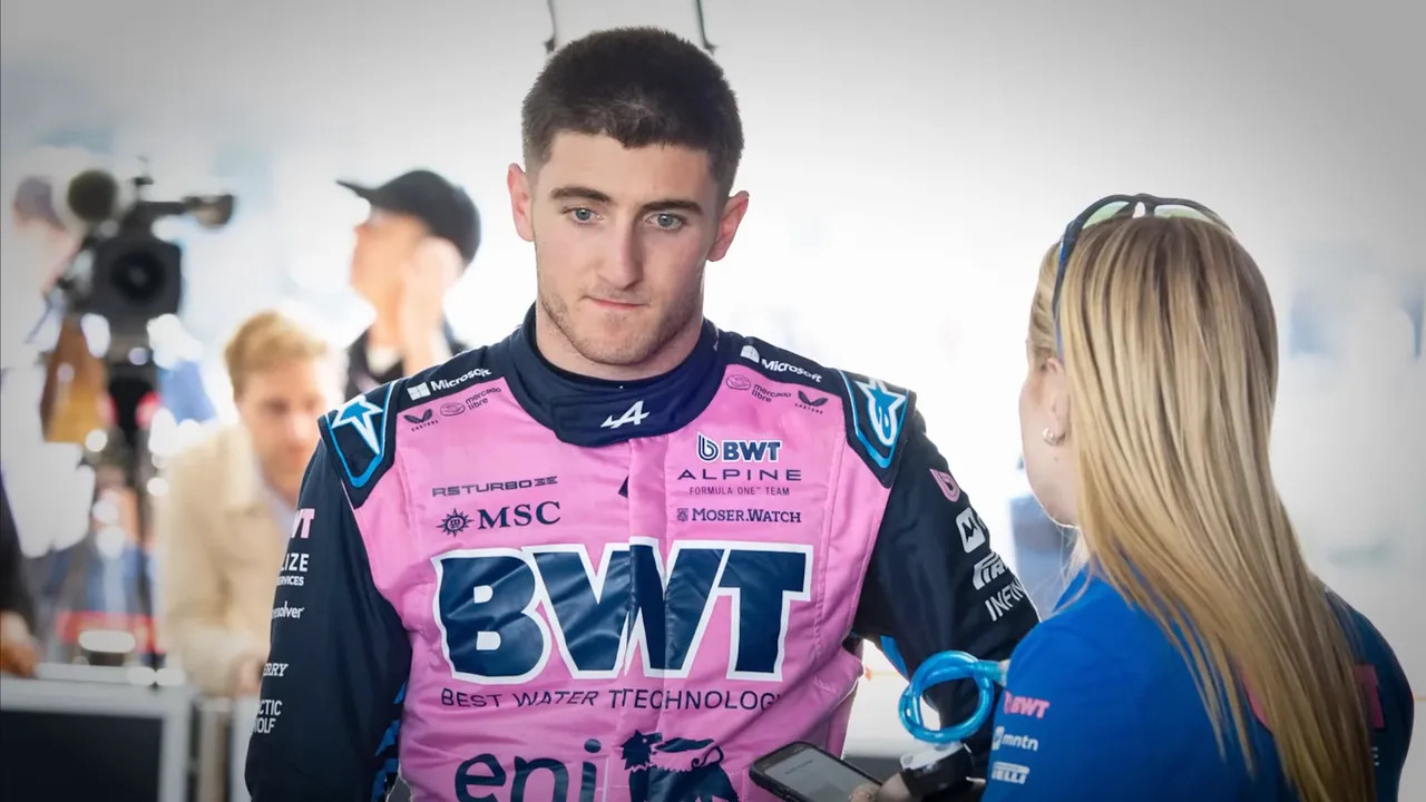 Formula 1 driver in a pink BWT racing suit speaking with a team member during an interview in the paddock.