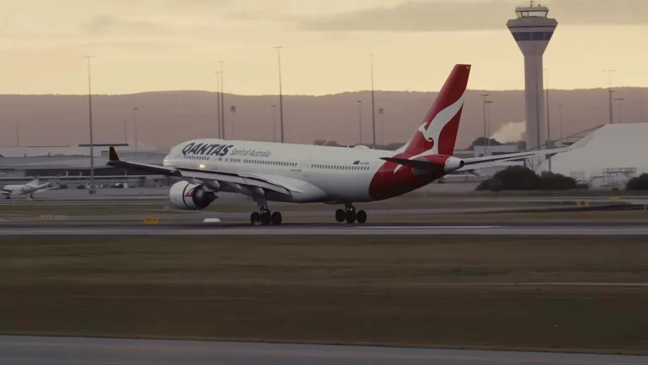 Qantas A330 widebody aircraft landing with airport control tower in background
