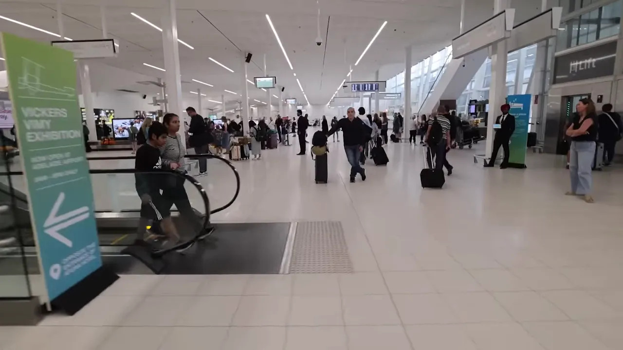 Spacious, bright Adelaide domestic terminal concourse with passengers and escalators